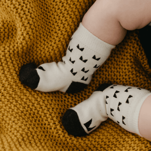 Merino Wool Baby Socks by Mosey featuring a modern design on a cozy blanket.