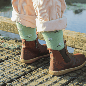 Child wearing Lamington merino crew socks in sage green with natural floral pattern made in New Zealand.