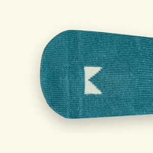 Close-up of Dusty Organic Cotton Baby Socks showing logo detail in gentle teal blue.