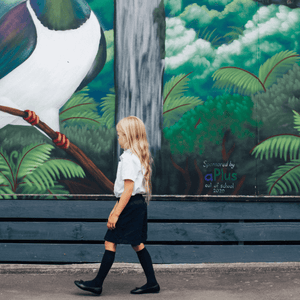 Child wearing Merino Wool Knee High Socks walking near a colorful mural with a bird.