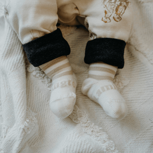 Merino Wool Crew Socks for Baby in Squirrel with oatmeal stripes on a cozy blanket.