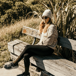 Woman sitting on a bench wearing a cozy sweater and Merino Wool Crew Socks