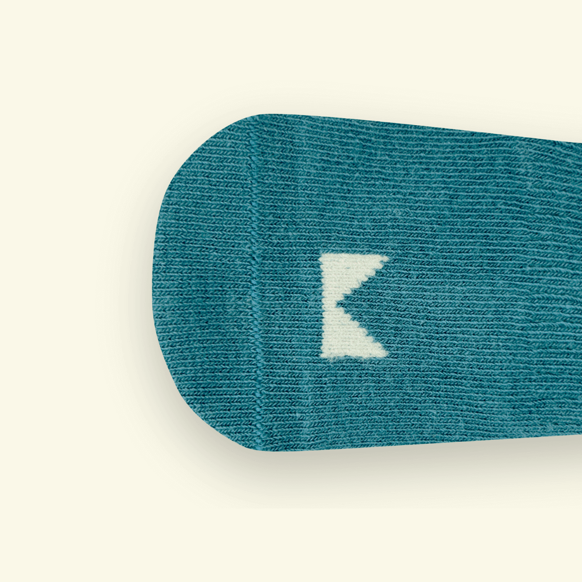 Close-up of Dusty Organic Cotton Baby Socks showing logo detail in gentle teal blue.