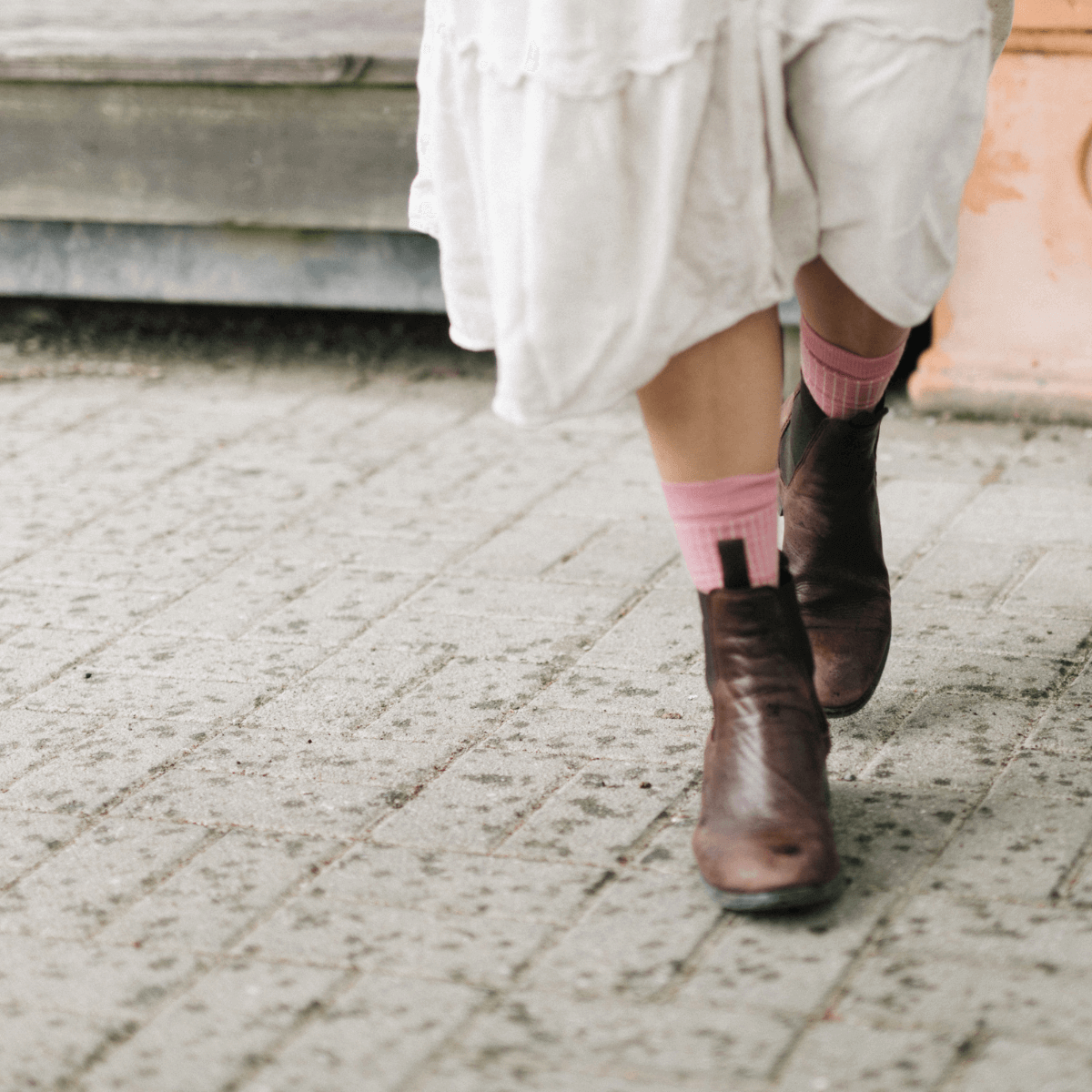 Woman walking in vintage pink Merino Wool Crew Socks, styled with a white dress and brown ankle boots.