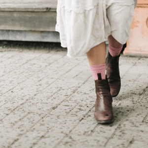 Woman walking in vintage pink Merino Wool Crew Socks, styled with a white dress and brown ankle boots.