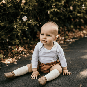 Merino Wool Knee High Socks for Baby in Owl worn by a baby sitting outdoors.