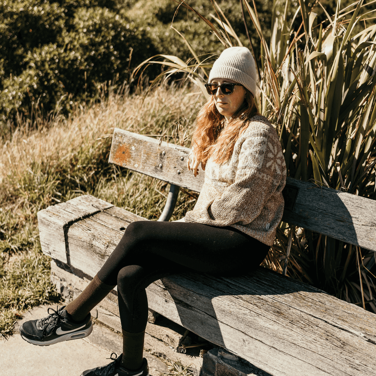Woman sitting on a bench wearing a cozy sweater and Merino Wool Crew Socks