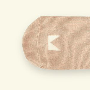 Organic Cotton Baby Socks in Oatmeal with a Mosey logo near the toe, soft and snug for tiny feet.
