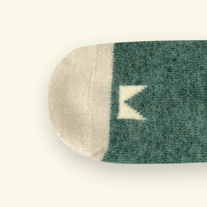 Close-up of Merino Wool Baby Socks in Rook showing logo pattern and color blend.