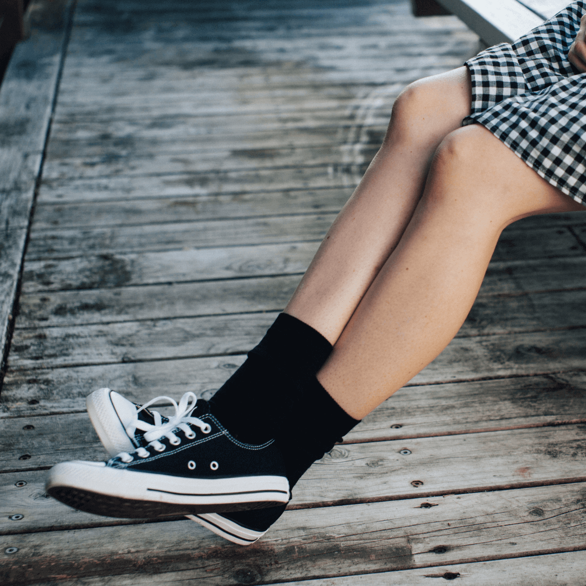 Merino Wool Crew Socks for Woman in black worn with black sneakers on wooden surface.