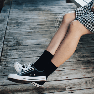 Merino Wool Crew Socks for Woman in black worn with black sneakers on wooden surface.